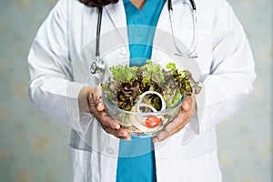 Nutritionist doctor holding salad vegetable in glass bowl to instruction healthy food.