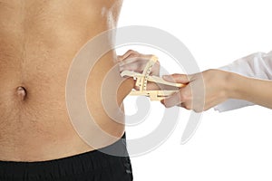 Nutritionist measuring man`s body fat layer with caliper on white background