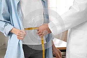 Nutritionist measuring young patient`s waist in clinic