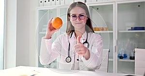 Nutritionist with orange and thumbs up