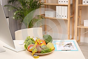 Nutritionist`s workplace with fruits, vegetables, measuring tape and body fat calipers photo