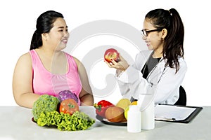 Nutritionist suggesting her patient to eat healthy food