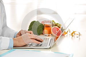 Nutritionist working with laptop at desk in office