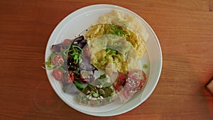 A nutritious brunch serving with fluffy scrambled eggs, a vibrant mixed salad, avocado toast, and seeds.