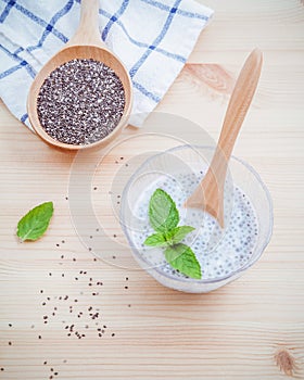 Nutritious chia seeds museli and peppermint leaves with wooden spoon for diet foods ingredients setup on wooden background .