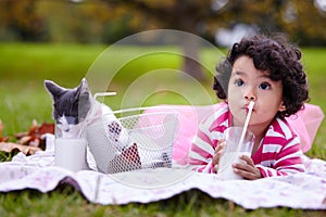 Nutritious and delicious. an adorable little girl drinking milk on the grass next to her kitten.