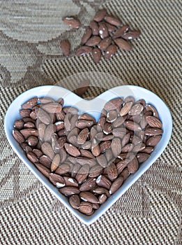 Nuts arranged in heart  on background. Healthy Food image close up almond on the cup plate. Love Texture on top view mock up