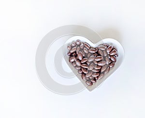 Nuts arranged in heart shape on background. Food image close up candy, chocolate milk, extra dark almond nuts. Love Texture on