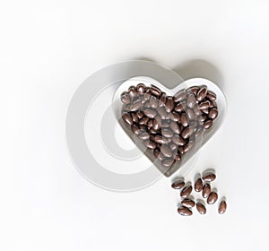 Nuts arranged in heart shape on background. Food image close up candy, chocolate milk, extra dark almond nuts. Love Texture on