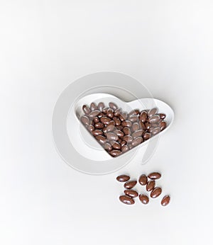 Nuts arranged in heart shape on background. Food image close up candy, chocolate milk, extra dark almond nuts. Love Texture on