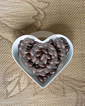 Nuts arranged in heart shape on background. Food image close up candy, chocolate milk, extra dark almond nuts. Love Texture