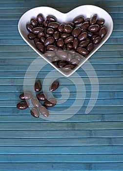 Nuts arranged in heart shape on background. Food image close up candy, chocolate milk, extra dark almond nuts. Love Texture