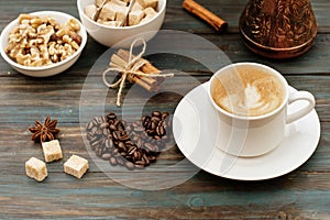 Nuts in bowl, coffeepot, heart-shaped coffee beans, cinnamon, anise, sugar, and cap of coffee on wooden background