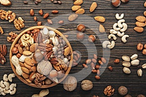 Nuts in bowls. Walnuts, pistachios, pecans, macadamia, almonds and other. Healthy food snacks mix on wooden background, top view