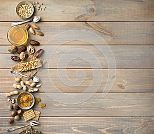 Nuts, dried fruits, honey and old spoons and forks on a wooden table background. Copy spase