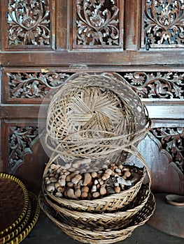 Nuts inside traditional bamboo bowls on the table in front of jati furniture javanese photo