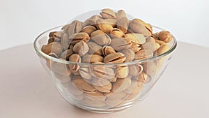 Nuts pistache rotate are on a table in a plate. Snack in transparent dish on an isolated white background are spinning