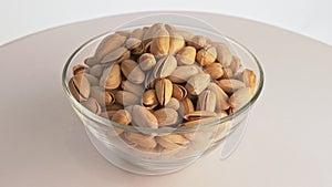 Nuts pistache rotate are on a table in a plate. Snack in transparent dish on an isolated white background are spinning