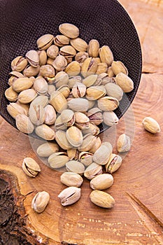 Nuts, of Pistacia in the shell poured from the dark Cup on wooden background