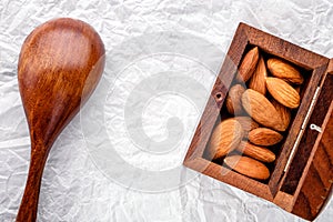nuts snack salted almonds and brown wooden spoon on white baking paper top view