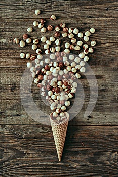 Nuts in waffle cone on wooden table, healthy snack, concept flat lay photography and content for food blog