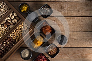 Nuts in a wooden box and spices in different shape of bowls