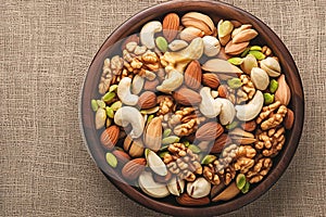 Nutty abundance Various nuts spill from wooden plate on table