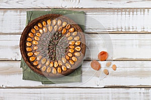 Nutty gluten-free cake with apricot nuts and pumpkin seeds, with filling, on a light wooden background.