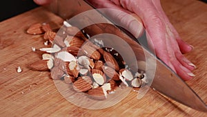 nutty perfection: woman hands cutting, chopping almonds closeup on wooden board