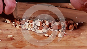 nutty perfection: woman hands cutting, chopping almonds closeup on wooden board