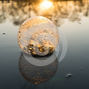 Glass ball on the hand, against the backdrop of a beautiful sunset. Sunset water. Reflection in water