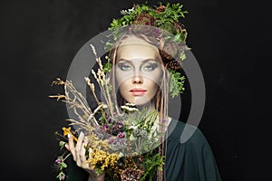 Nymph woman with wild flowers on black background