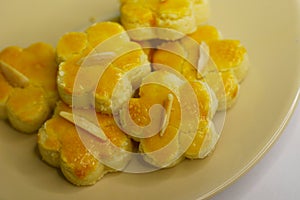 Nyonya almond cookies, piped into flower shapes, on a white saucer