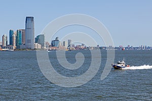 NYPD boat patrolling East River. In the background skyscrapers New Jersey.