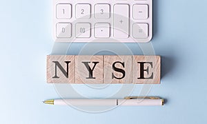 NYSE on wooden cubes with pen and calculator, financial concept