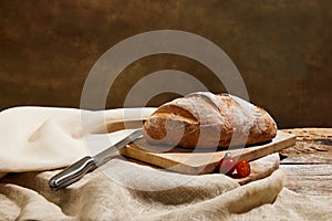 oaf of freshly baked sourdough bread with knife and tomatoes on napkin.