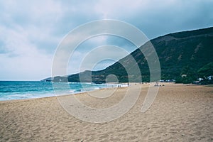 Oahu beach with big waves and many people on sand