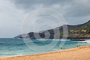 Oahu beach with people swimming in big waves