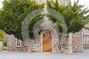 The oak door of Drumbo Parish Church flanked by two ancient Juniper trees in the County Down village of Drumbo in Northern Ireland