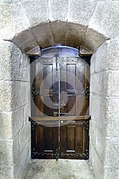 Oak door varnished with metal fittings and bar atranÃ¡ndola anchored in very thick granite stone walls in the palace of the Dukes