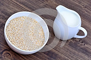 Oat in a ceramic bowl and pitcher with milk