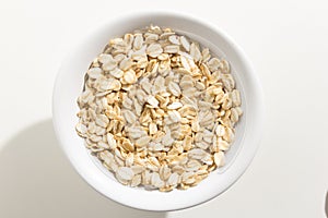 Oat cereal grain. Top view of grains in a bowl. White background