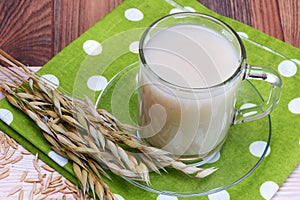 Oat decoction in a transparent mug, grains and ears