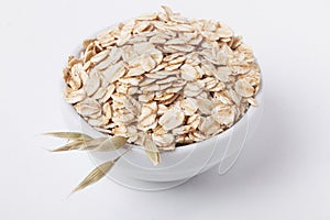 Oat flakes in a bowl with ears, isolated