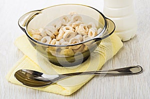 Oat flakes in bowl, spoon on napkin, bottle of yogurt