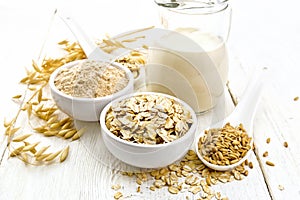 Oat flakes with flour and milk on white wooden board