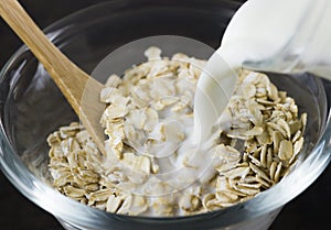 Oat flakes in glass bowl Pouring milk from jar, healthy eating vegetarian diet concept