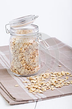 The oat flakes in glass jar on brown towel.