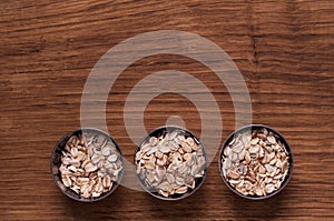 Oat flakes in metal bowl on brown wooden table