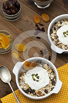 Oat flakes with nuts, dried fruit mix in bowl over rustic wooden table, . Healthy breakfast food